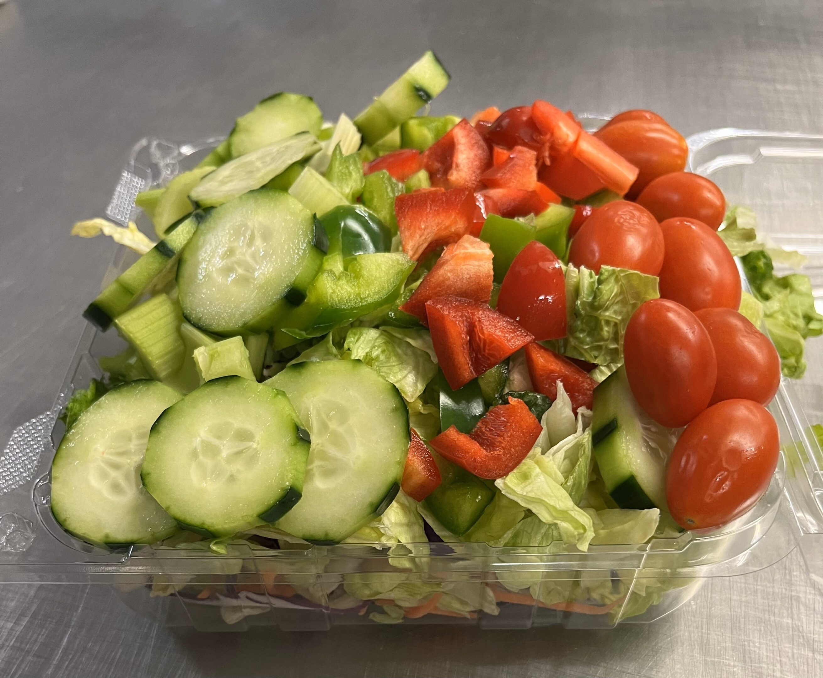 A salad with cucumbers, tomatoes and lettuce in it.
