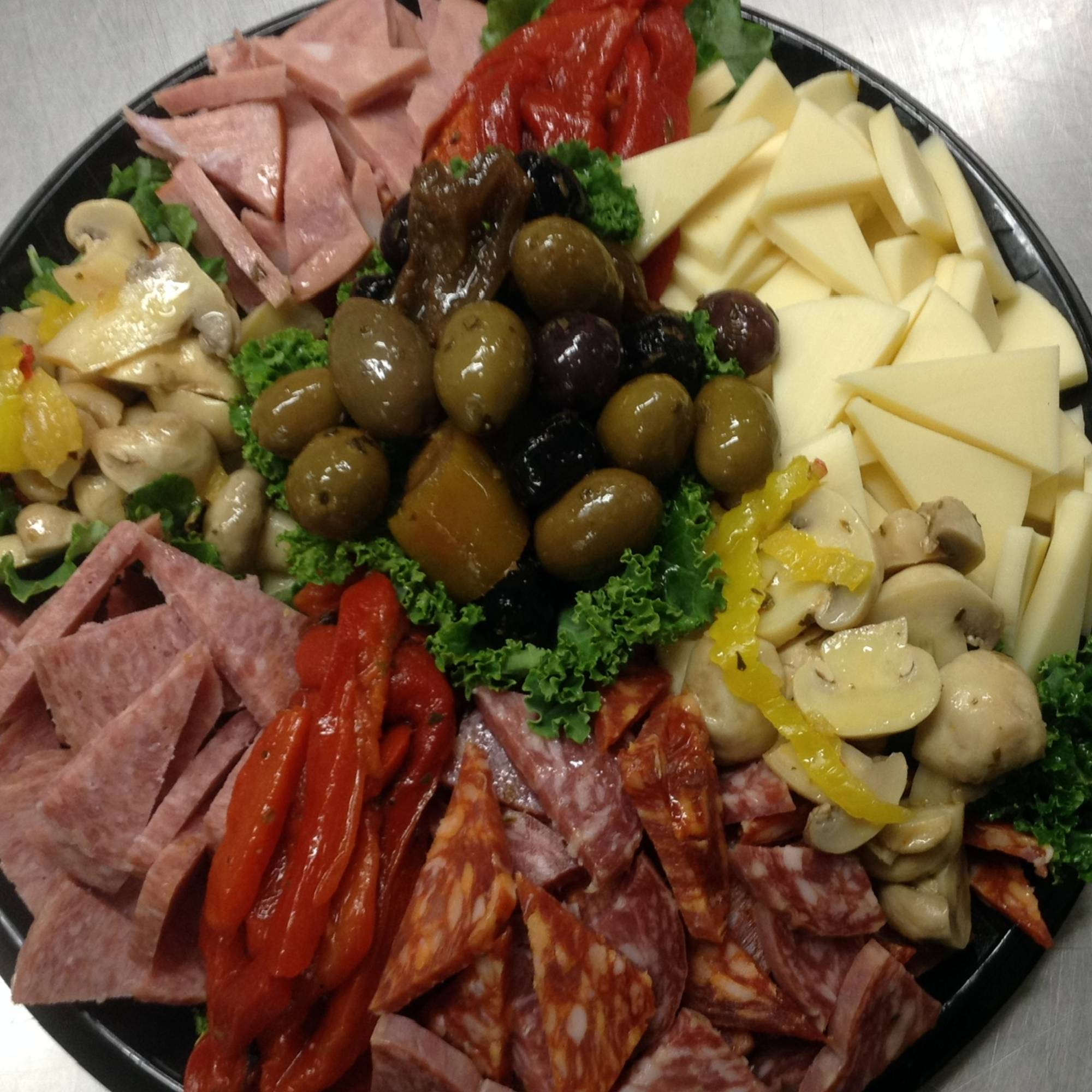 A platter of food with meat, cheese and olives.