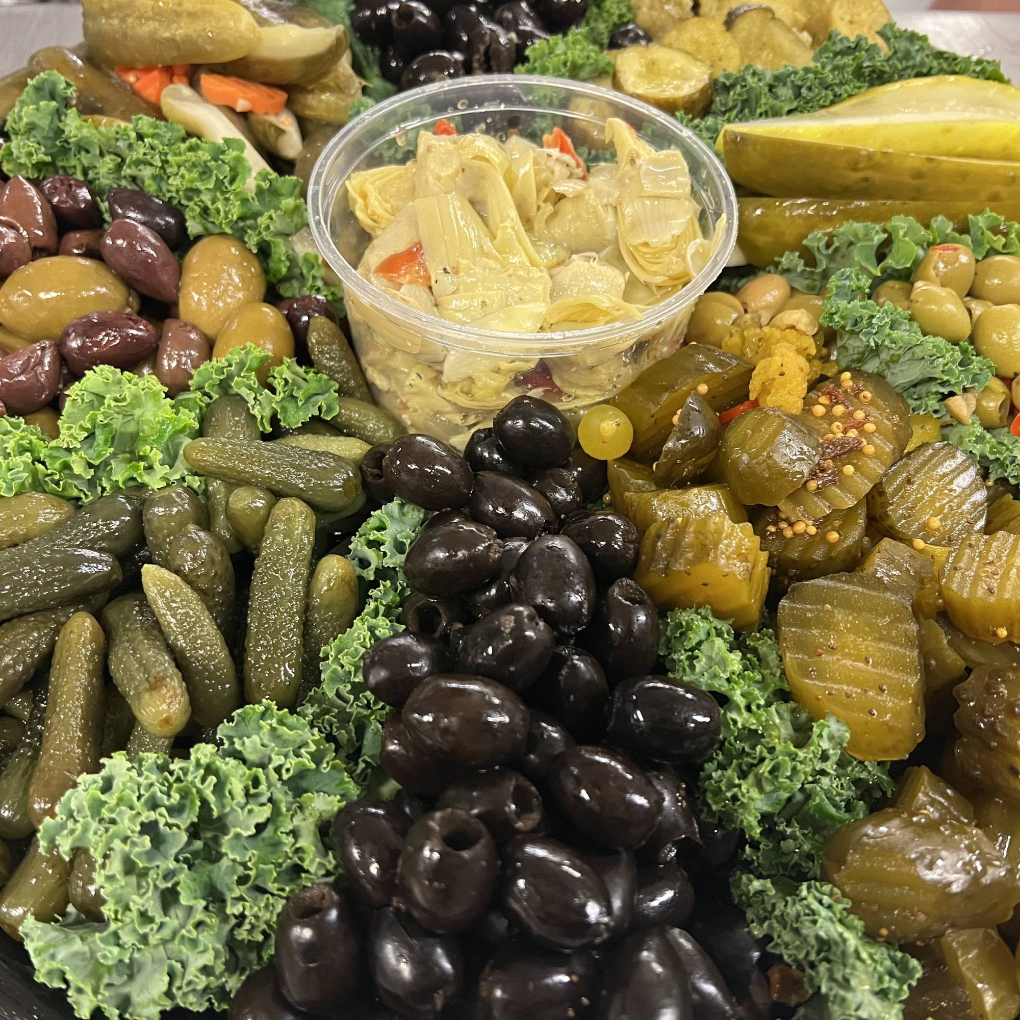 A large platter of olives, pickles and other vegetables.