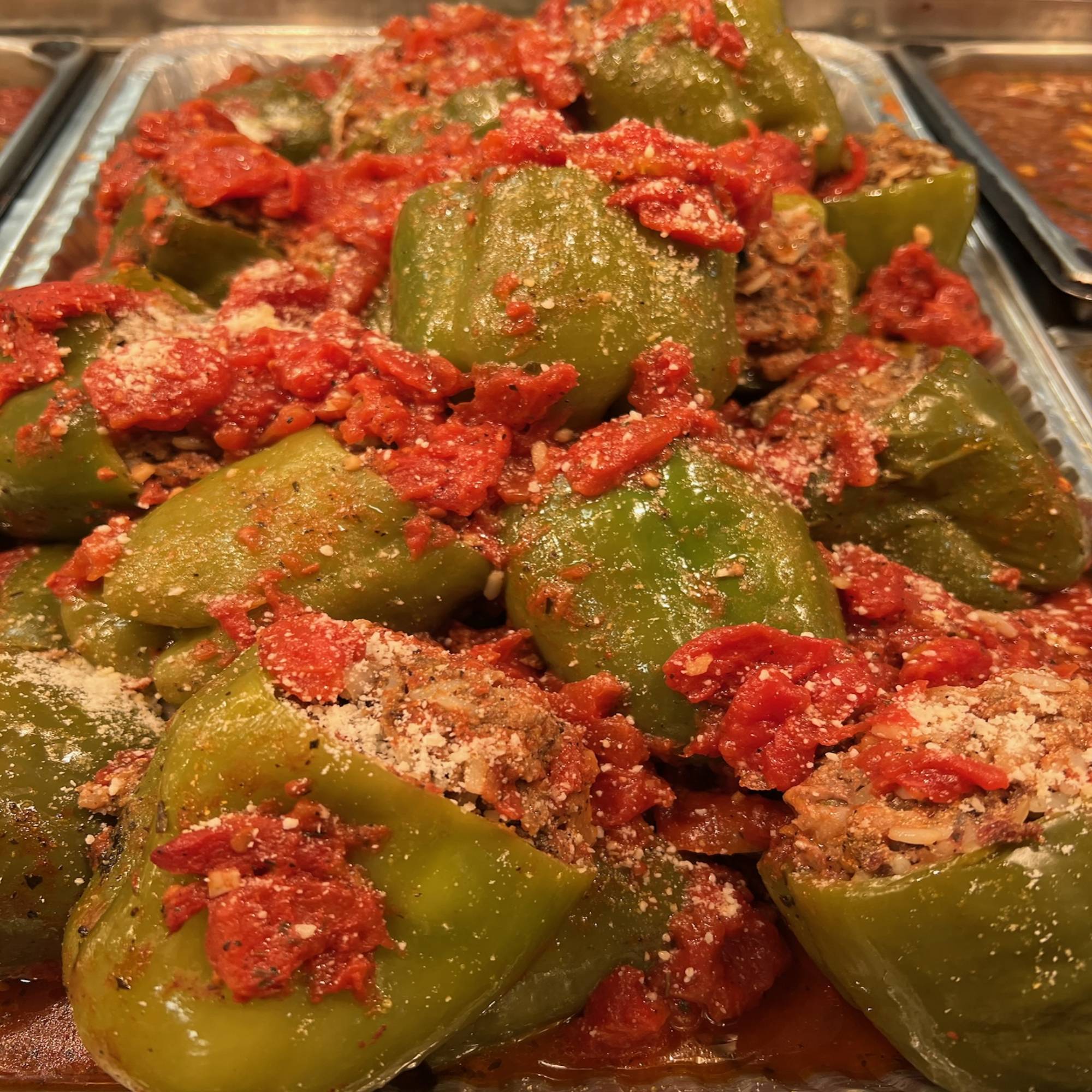 A tray of stuffed peppers with meat and tomato sauce.