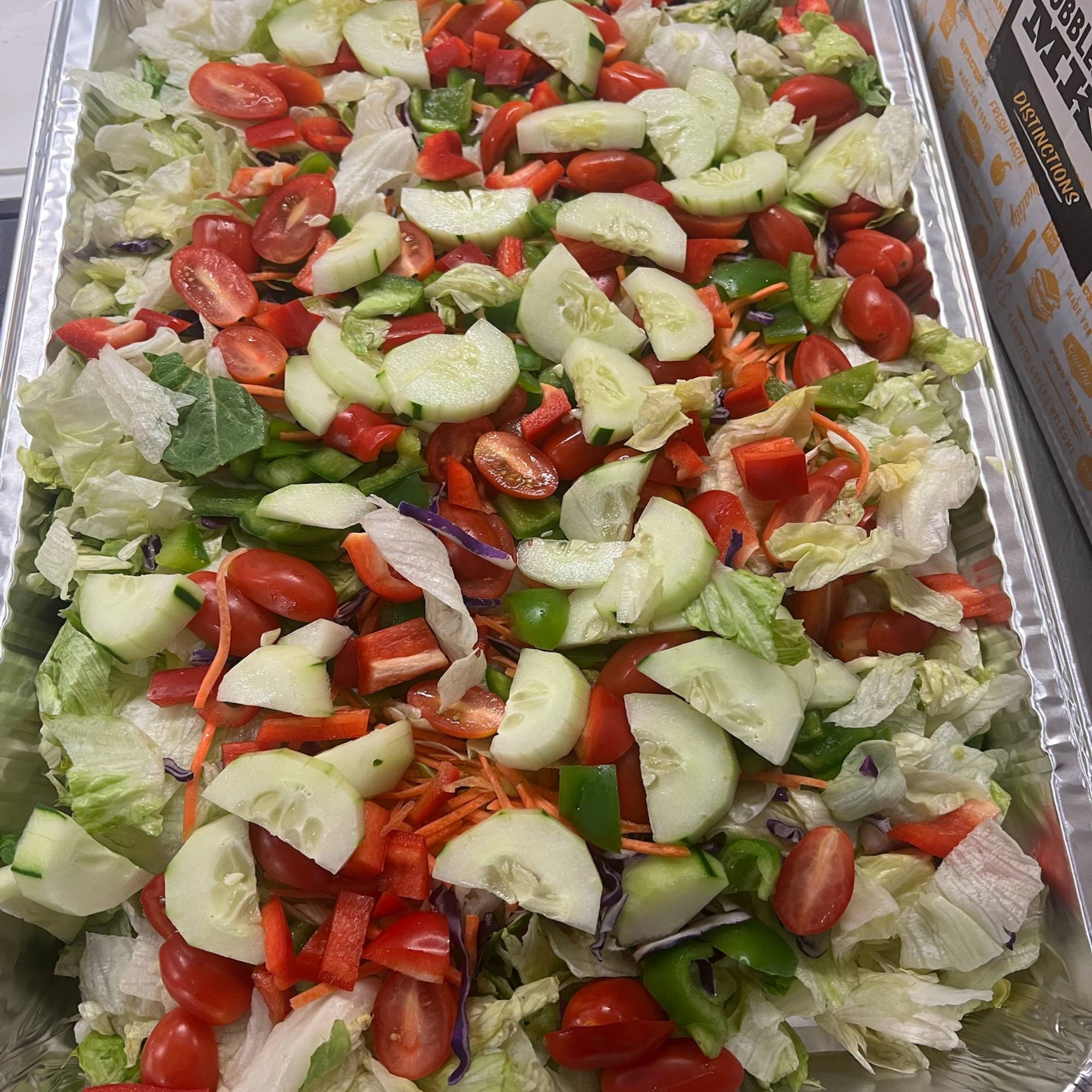 A tray of salad with tomatoes, cucumbers and lettuce.