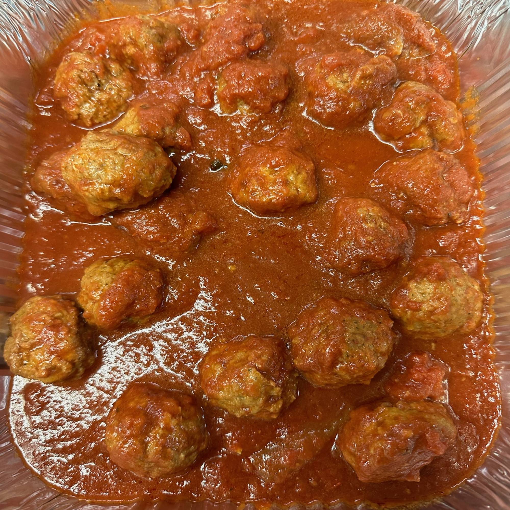 A bowl of meatballs in sauce on top of a table.