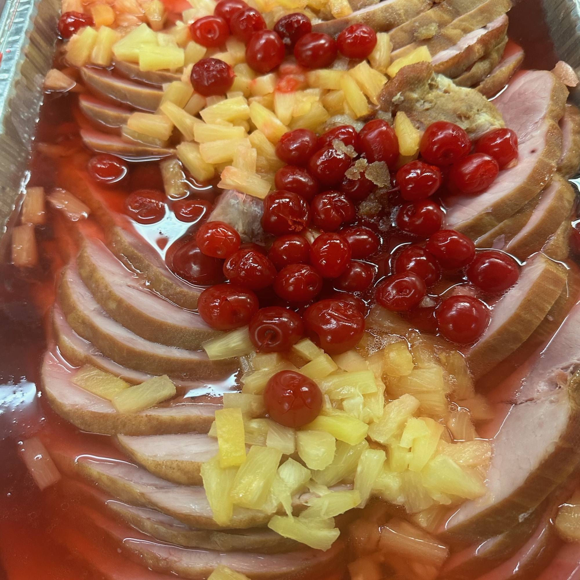 A tray of food with ham and cherries.