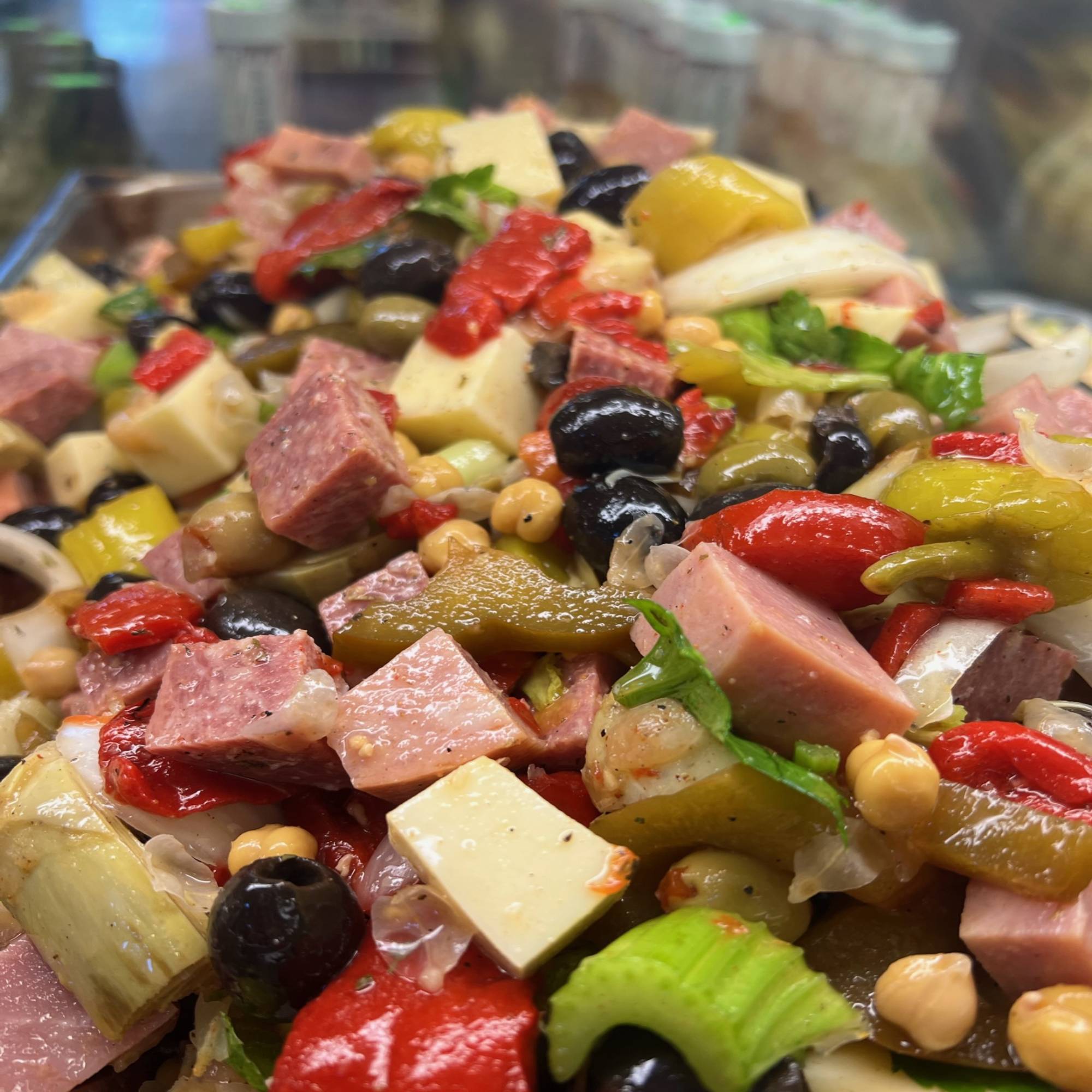 A close up of a salad with ham and olives