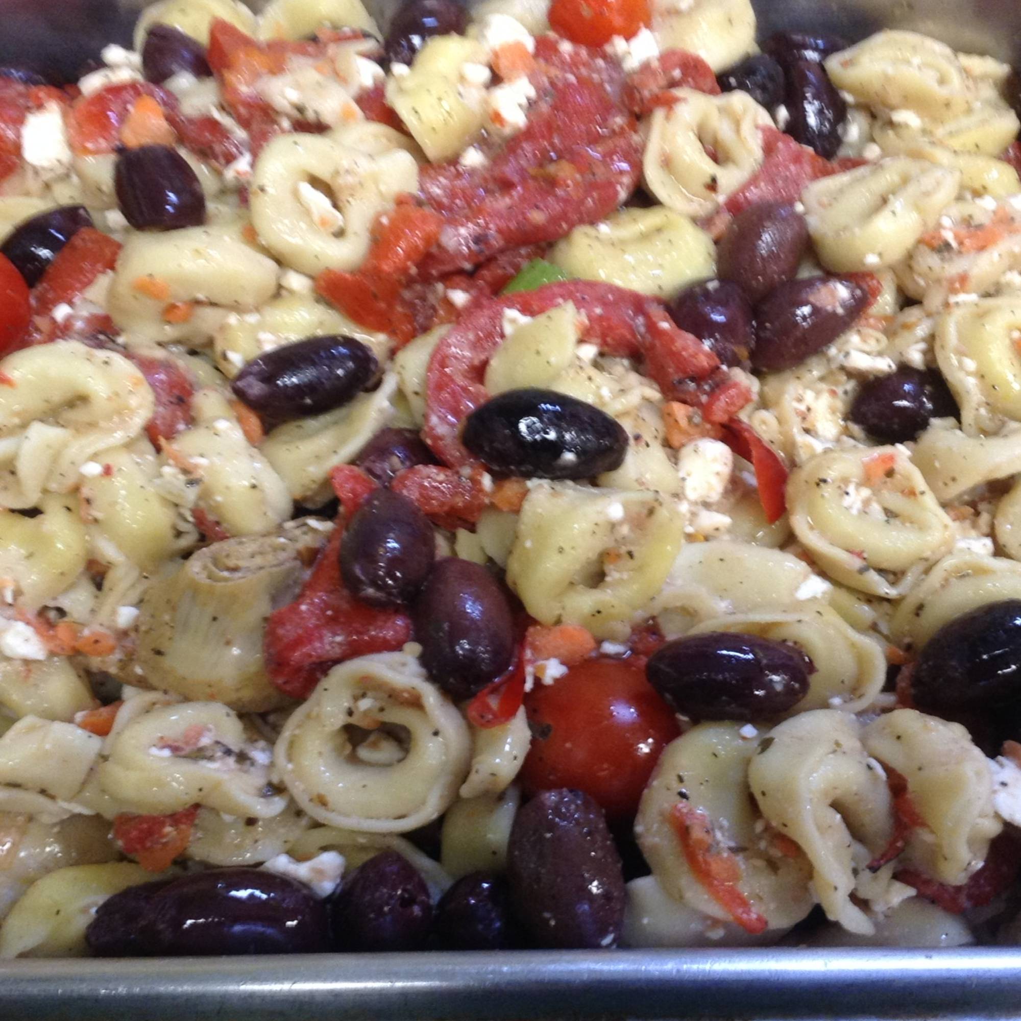 A close up of pasta with olives and tomatoes