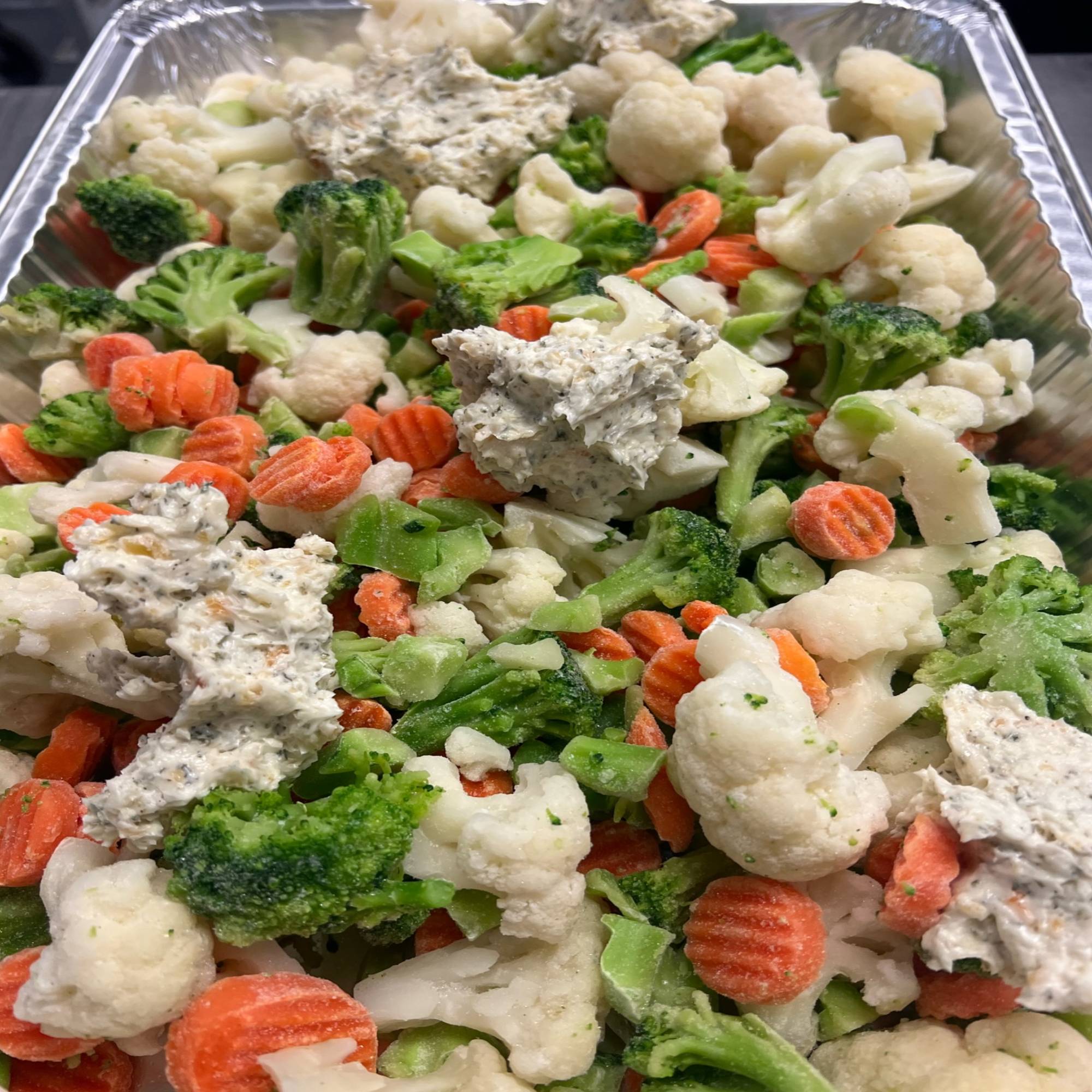 A tray of food with broccoli, carrots and cauliflower.