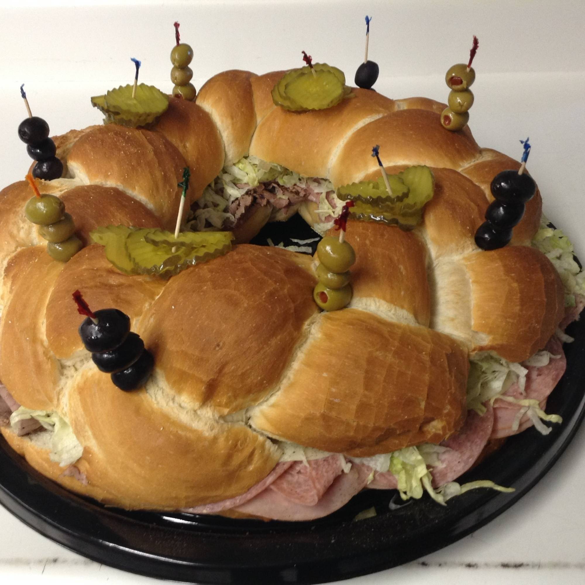 A sandwich platter with pickles and olives on it.