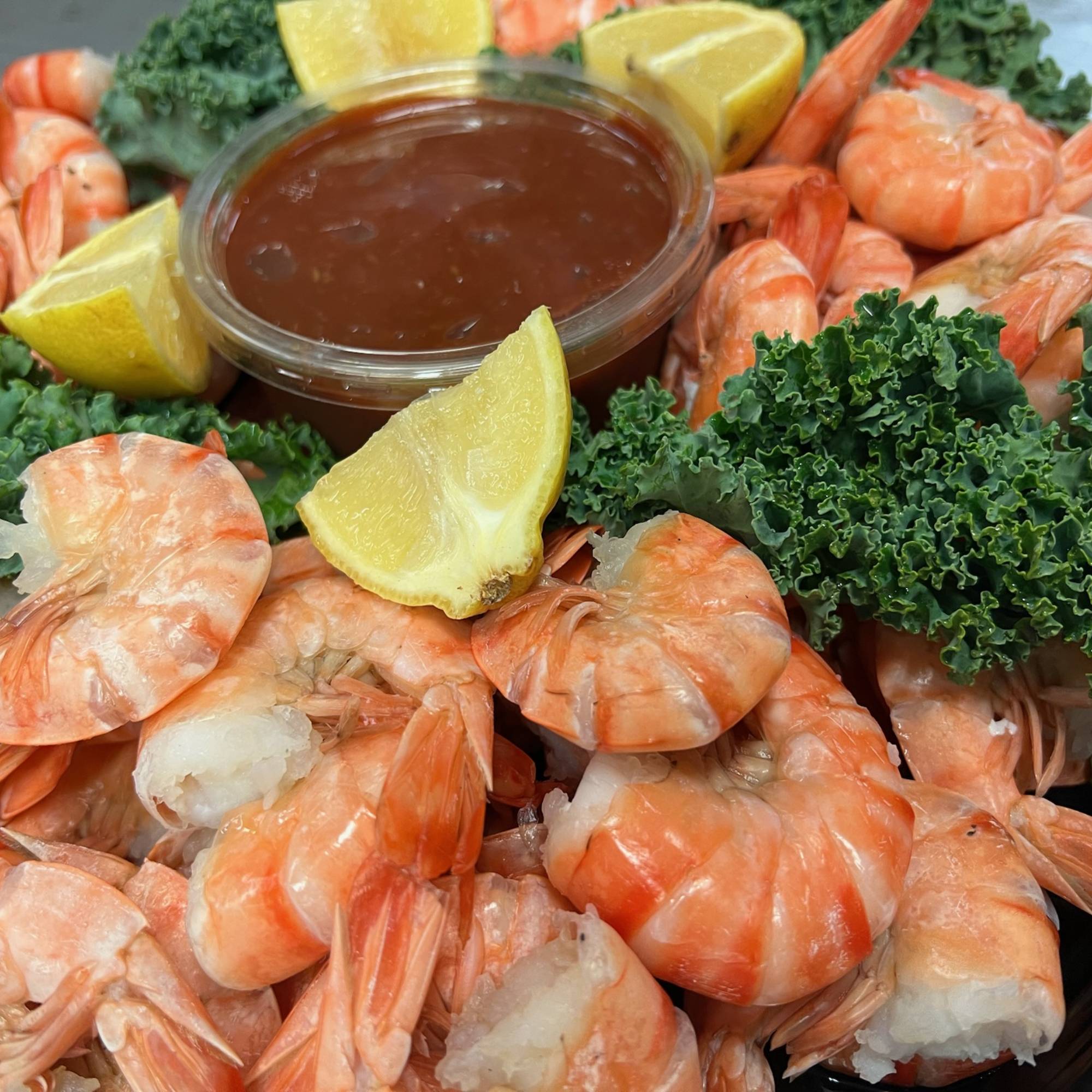 A platter of shrimp with lemon wedges and broccoli.