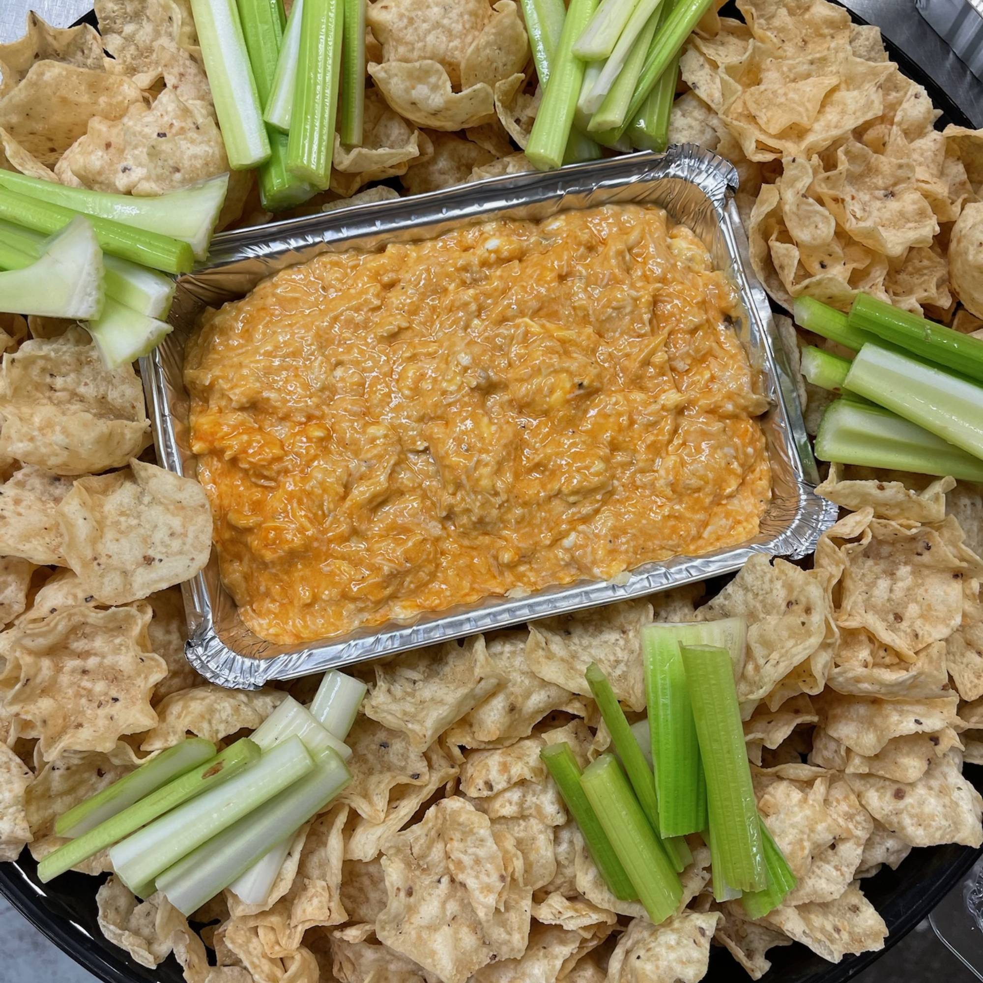 A tray of food with celery and crackers on it.