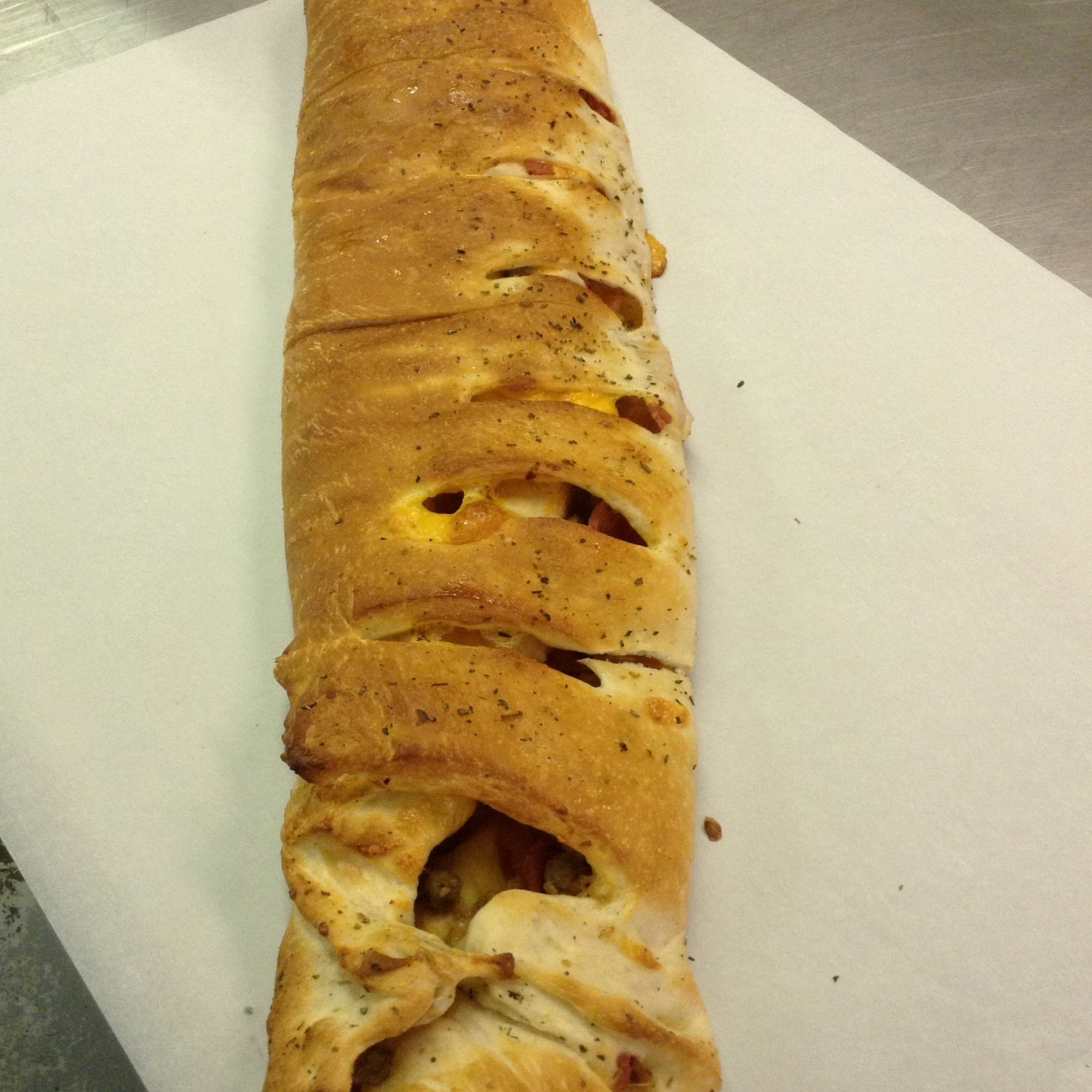 A long pastry with some kind of meat on it