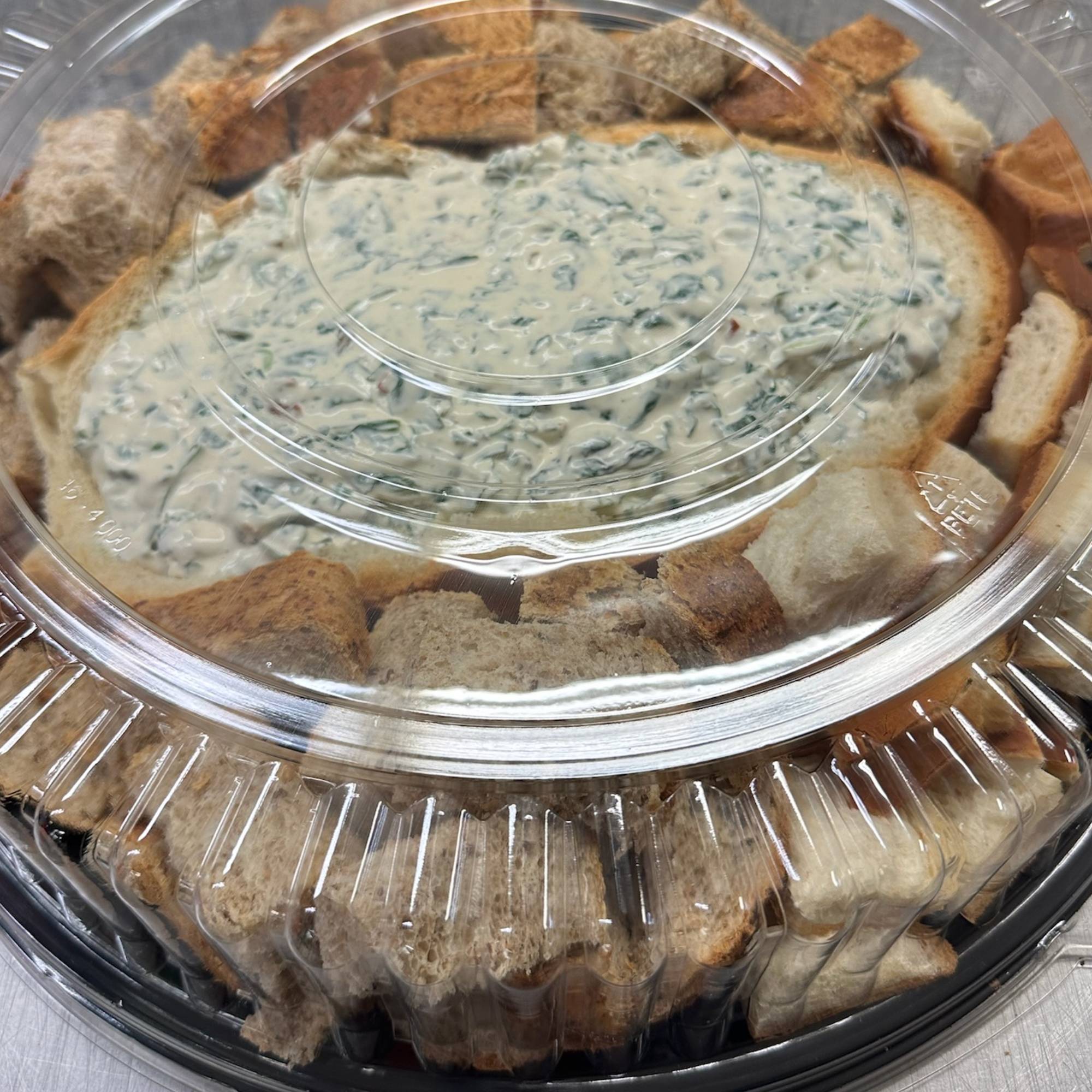 A bowl of bread and dip on top of a platter.
