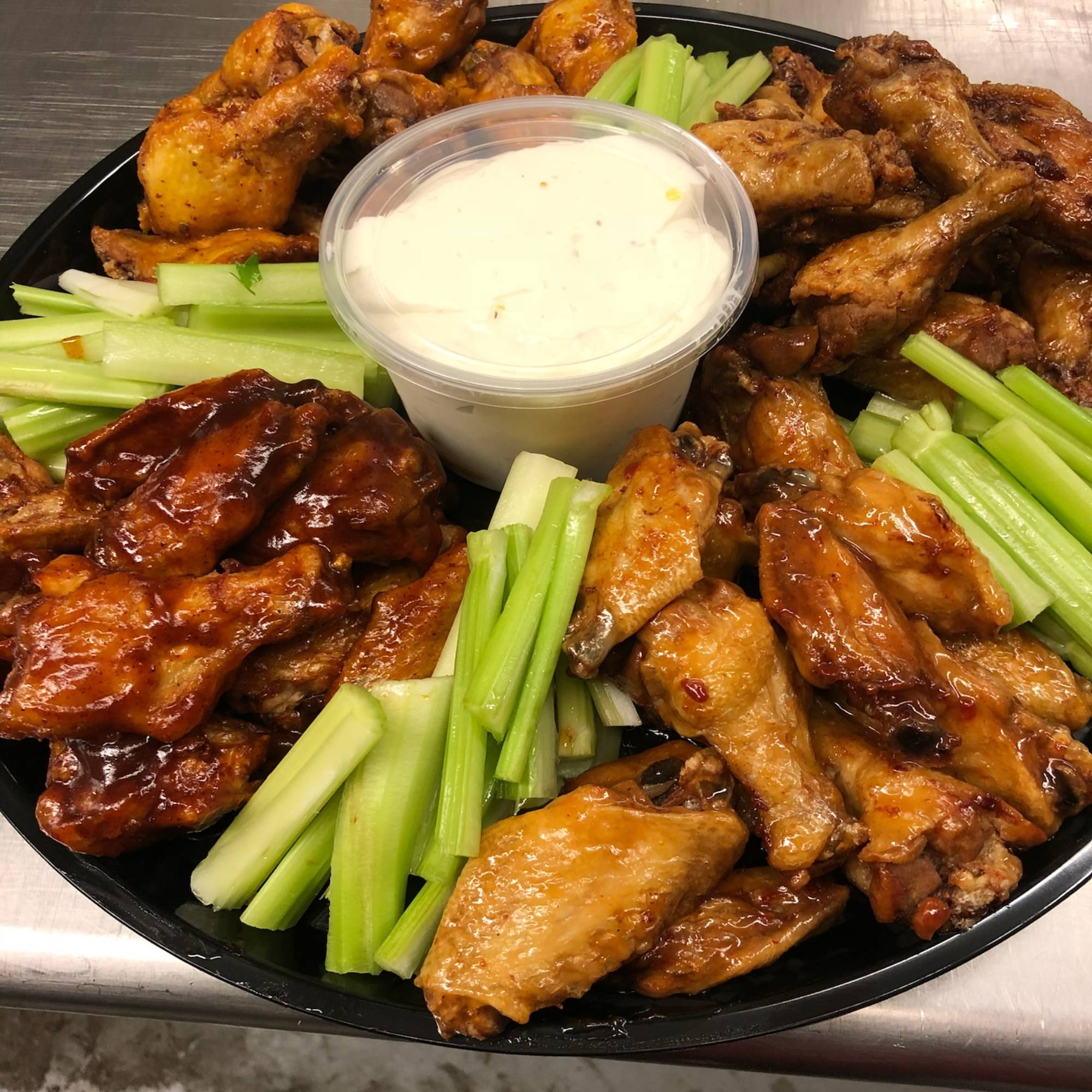 A plate of chicken wings and celery sticks with dip.
