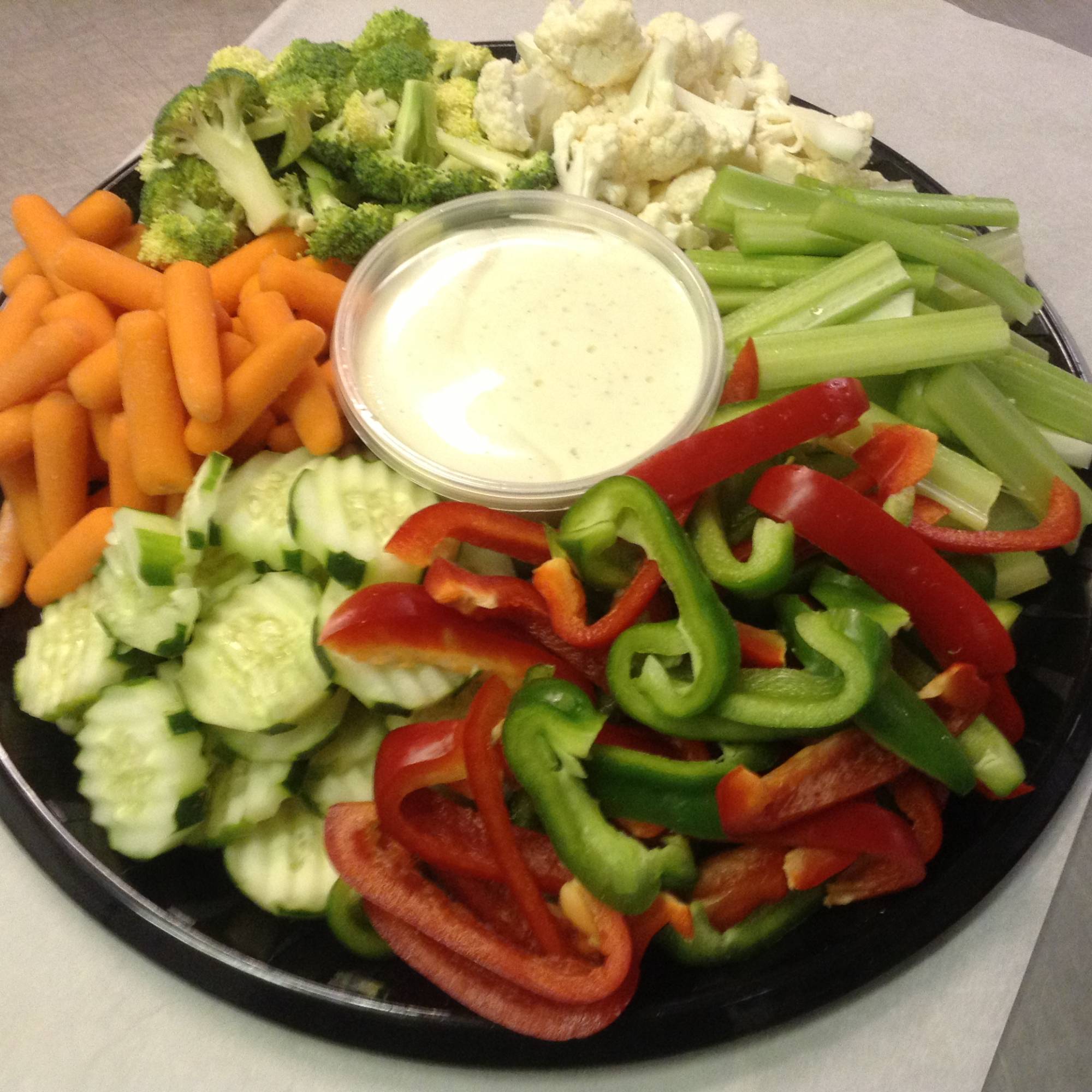 A platter of vegetables with dip on the side.