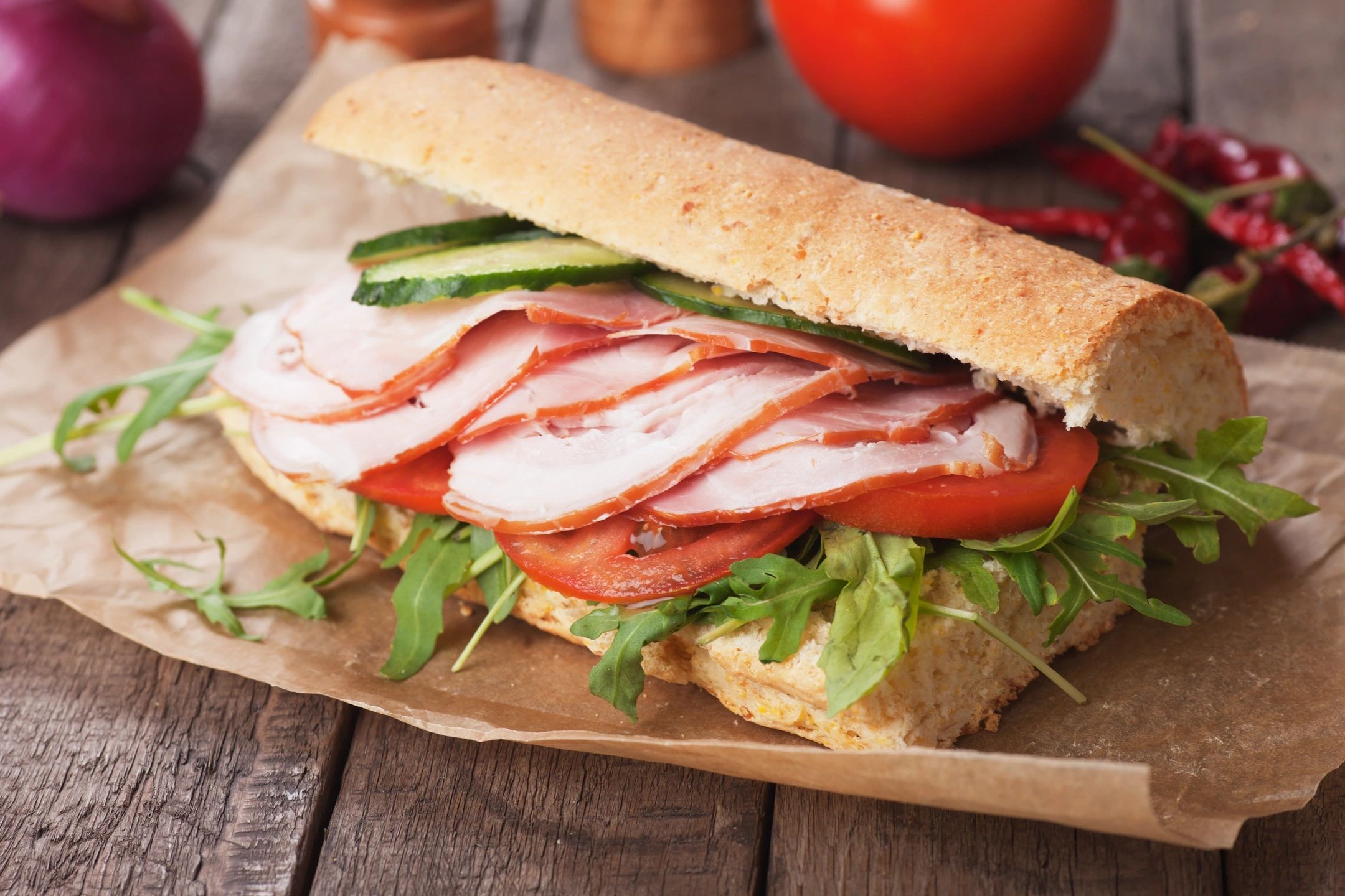 A sandwich with meat, tomato and lettuce on it.